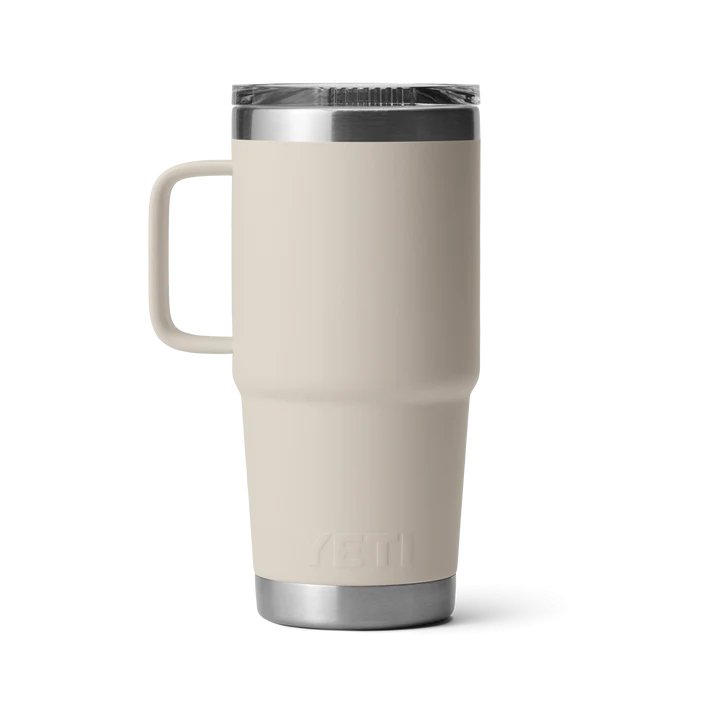 Ein YETI® Reisebecher Rambler 20 Oz in Cape Taupe mit Griff, auslaufsicherem Deckel und Edelstahlakzenten steht aufrecht vor weißem Hintergrund.