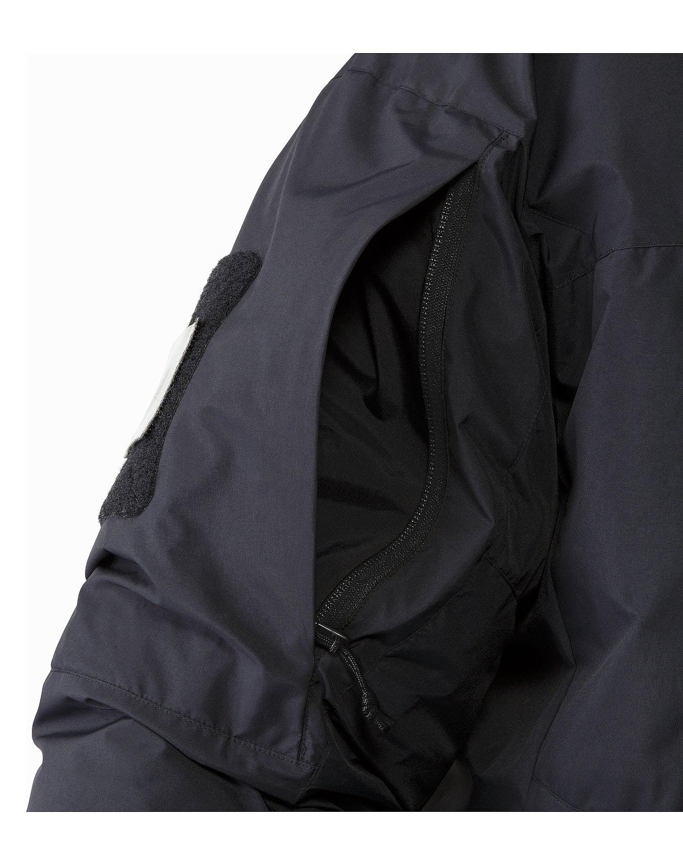 Nahaufnahme eines dunklen Arc'teryx Cold WX Jacket SV Gen1.4 Ärmels von ARC'TERYX LEAF mit einer offenen Reißverschlusstasche mit schwarzem Innenfutter und GORE WINDSTOPPER, dargestellt auf einem einfarbig weißen Hintergrund.