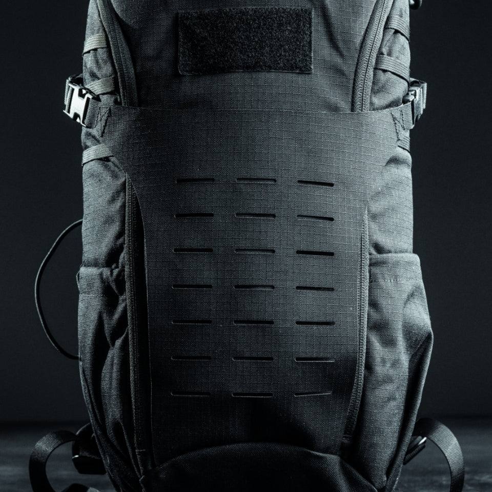 Eine Nahaufnahme des EBERLESTOCK Eberlestock Bandit Pack, eines schwarzen taktischen Rucksacks mit strapazierfähigem Material, mehreren Gurten, Seitentaschen und einem lasergeschnittenen MOLLE-Panel auf der Vorderseite vor einem dunklen Hintergrund.
