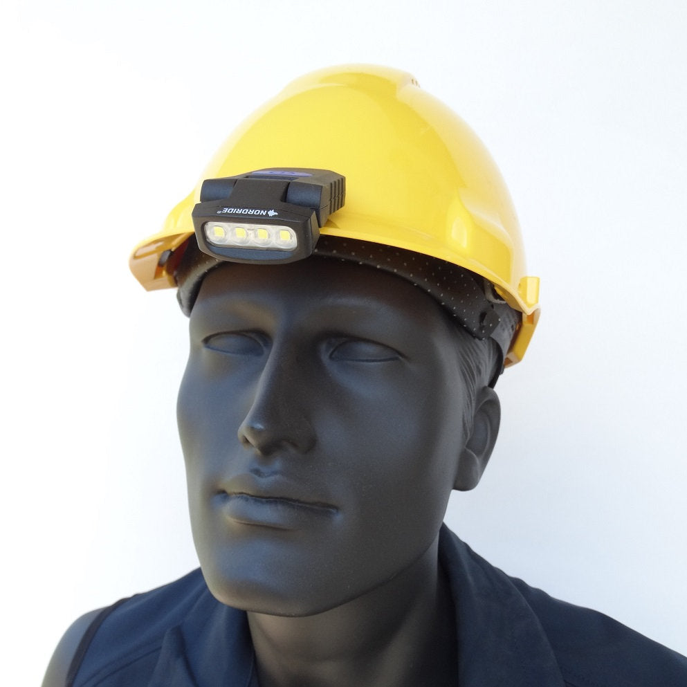Eine schwarze Schaufensterpuppe trägt einen gelben Schutzhelm mit einer auf der Vorderseite montierten NORDRIDE Nordride Clipleuchte Scout LED-Lampe, ideal für die Außenbeleuchtung, abgebildet vor einem schlichten weißen Hintergrund.