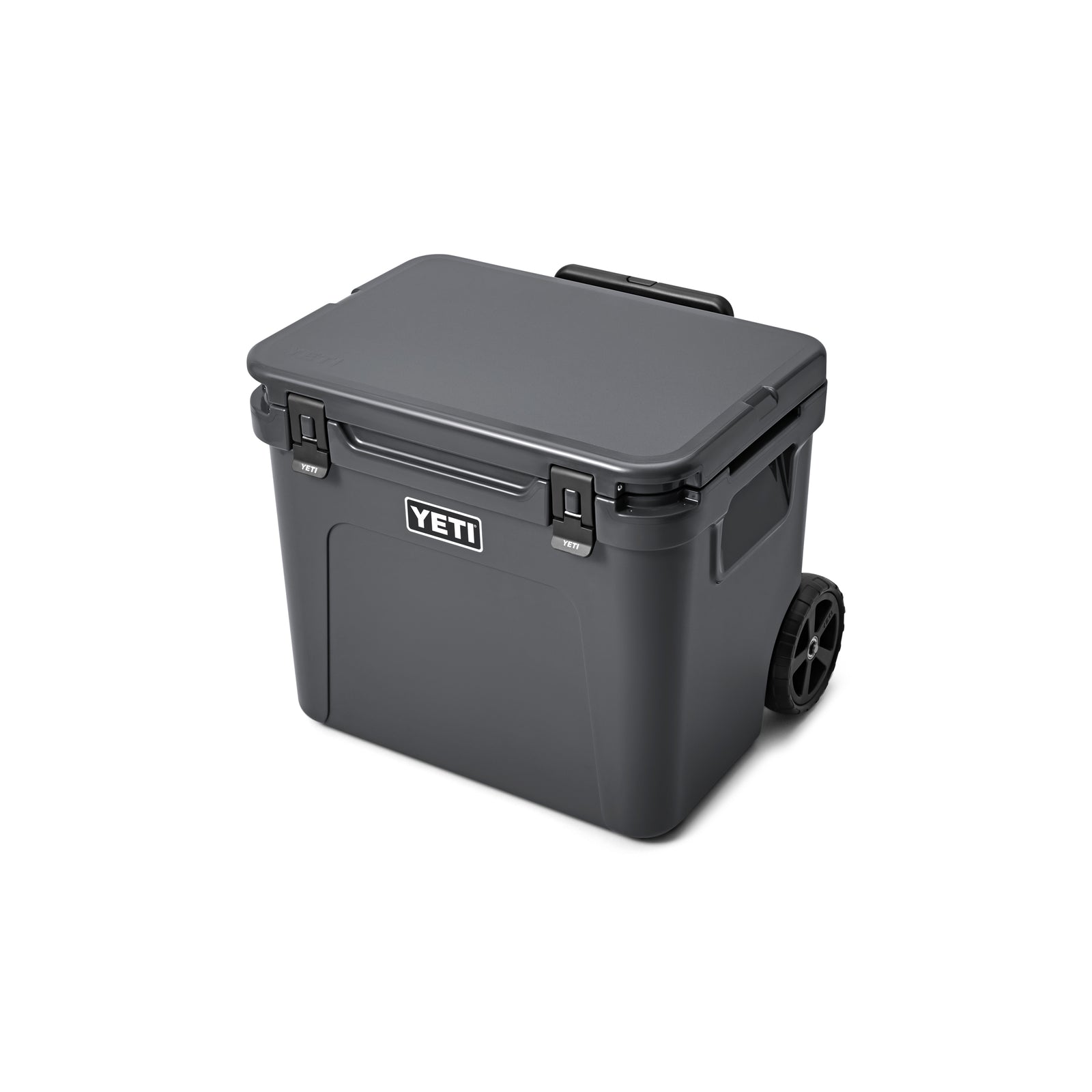 Die YETI® Kühlbox Roadie 60 - Charcoal ist eine dunkelgraue, rechteckige Kühlbox mit Griff, zwei Rädern für den einfachen Transport, sicheren Verschlüssen an der Vorderseite und dem kultigen YETI-Logo.