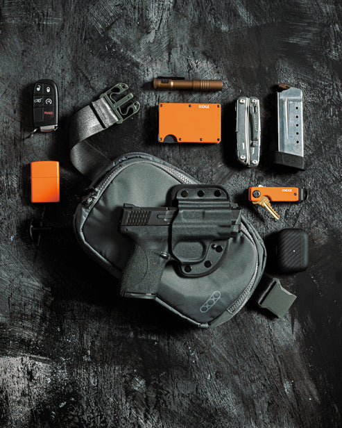 Eine Auswahl an EDC-Utensilien auf einer dunklen Oberfläche, darunter eine Handfeuerwaffe in einem Holster auf der EBERLESTOCK Fade Flex Micro Tasche sowie ein Taschenmesser, eine Taschenlampe, eine orangefarbene Brieftasche, ein Feuerzeug, ein Multitool, ein Magazin, ein Autoschlüssel und andere Werkzeuge.