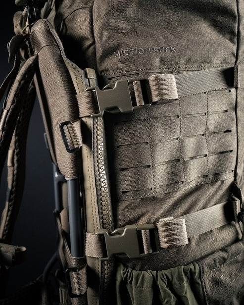 Nahaufnahme des robusten olivgrünen EBERLESTOCK Mission Rucksacks mit strapazierfähigen Riemen, Schnallen und MOLLE-Gurtband. Der aufgestickte Schriftzug "MISSION RUCK" unterstreicht das taktische und robuste Design.
