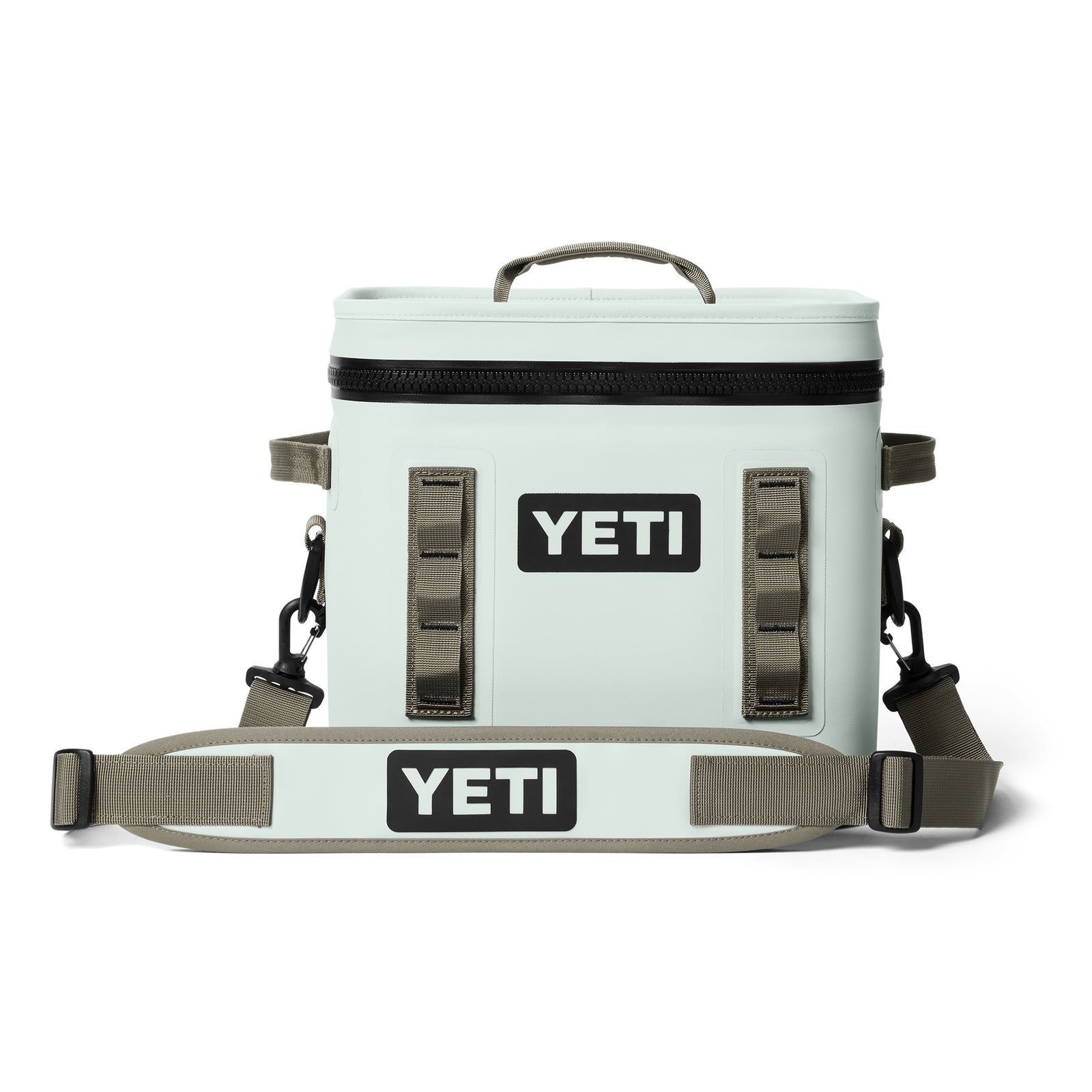 Die YETI® Kühltasche Hopper Flip® 12 - Ridgeline ist eine hellgraue Kühltasche mit schwarzem Reißverschluss, hellbraunen Seitengriffen, einem verstellbaren Schultergurt und dem YETI-Logo in Schwarz und Weiß.