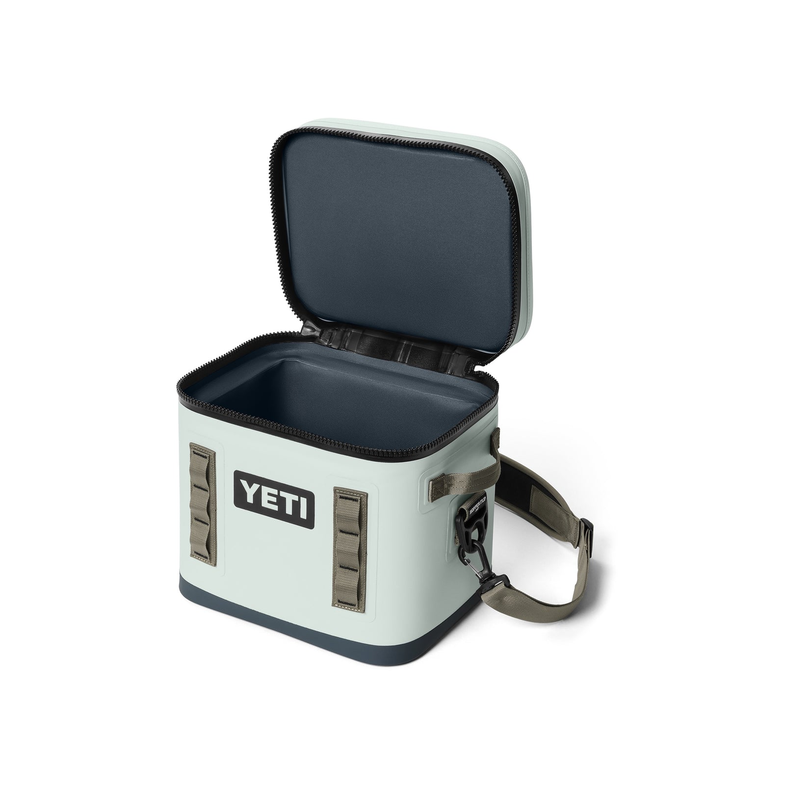 Eine hellgraue YETI® Kühltasche Hopper Flip® 12 - Ridgeline mit geöffnetem Reißverschlussdeckel, leeres Inneres sichtbar. Mit Schultergurt, seitlichen Griffen, auslaufsicherem Design und dem YETI-Logo auf der Vorderseite.