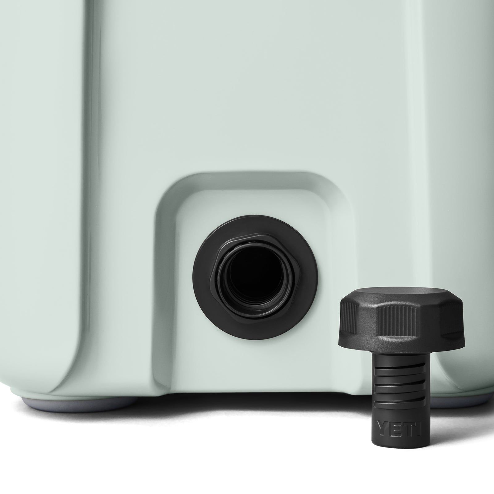 Die Nahaufnahme der YETI® Kühlbox Roadie 15 - Ridgeline zeigt die schwarze Ausgussöffnung mit Gewinde; daneben befindet sich ein schwarzer Schraubverschluss mit YETI-Logo.