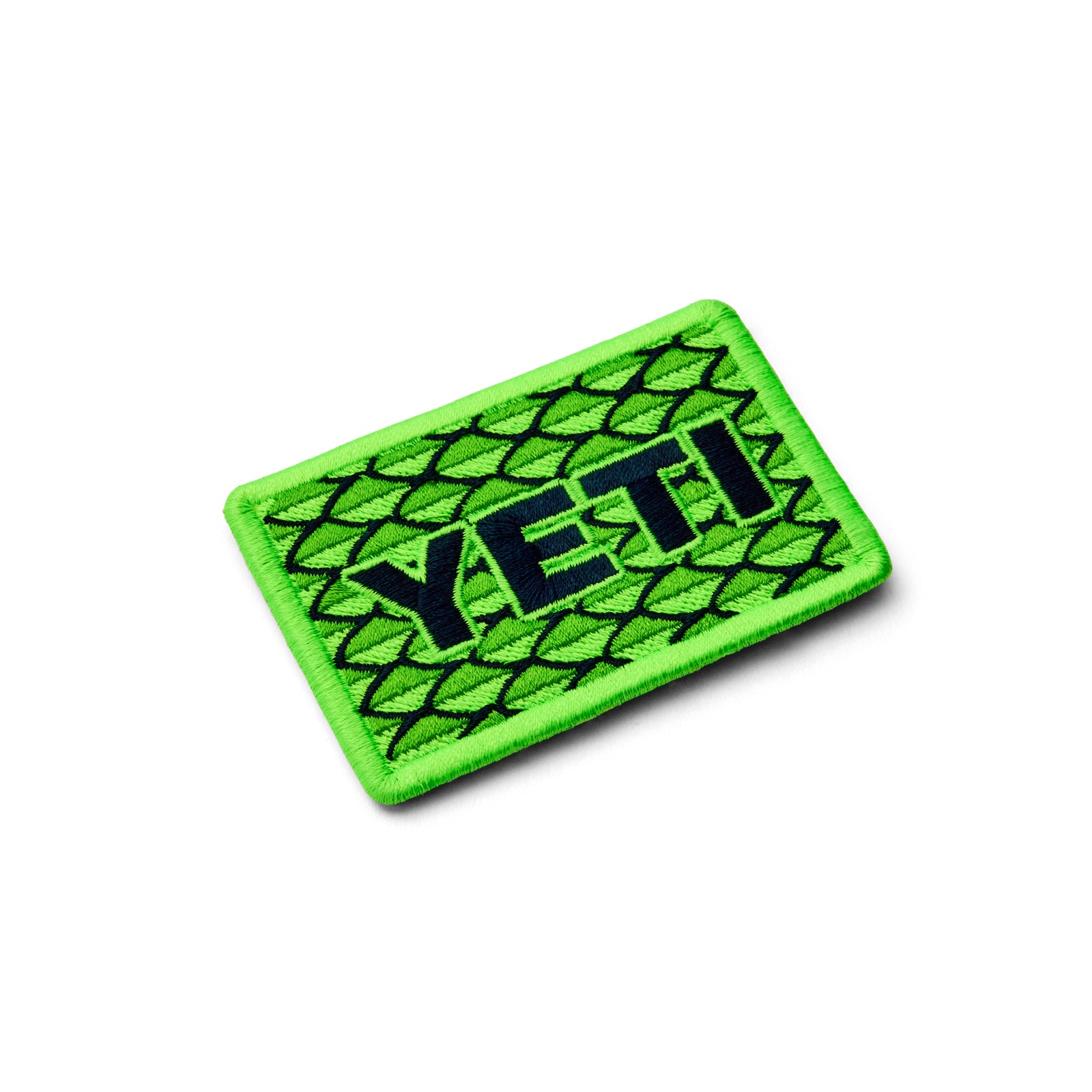 Der YETI® Scales Patch ist ein rechteckiger Aufnäher von YETI, bestickt mit einem hellgrünen Rand und Hintergrund, dunkelgrünen Schuppen und einem fetten schwarzen Schriftzug - ideal als Klettaufnäher für Ihre Outdoor-Ausrüstung.