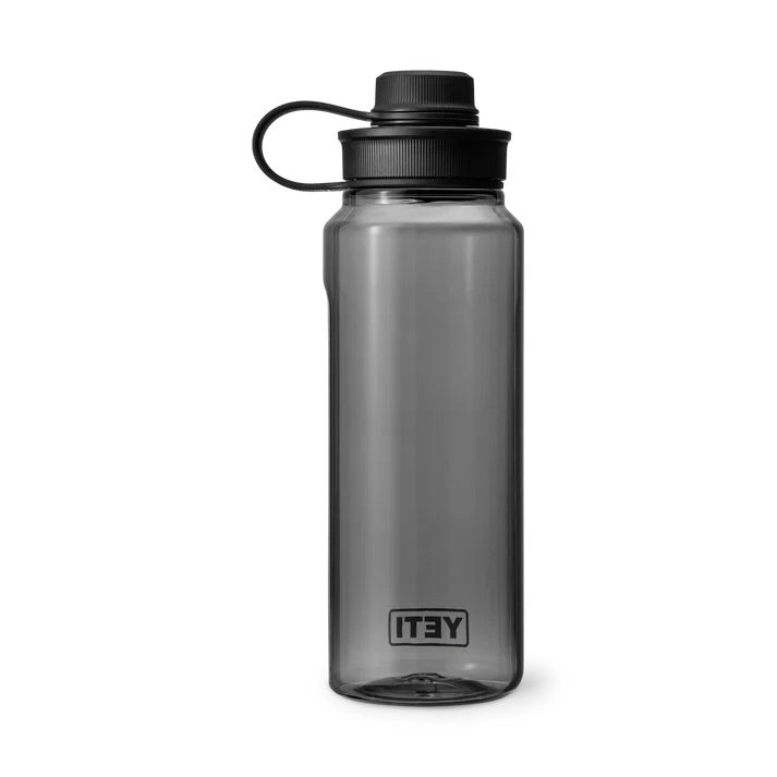 Die YETI® Yonder™ 1L Wasserflasche ist eine bruchfeste, transparente graue BPA-freie Wasserflasche von YETI mit schwarzem Schraubdeckel und flexiblem Halteband sowie Markenlogo am Boden.