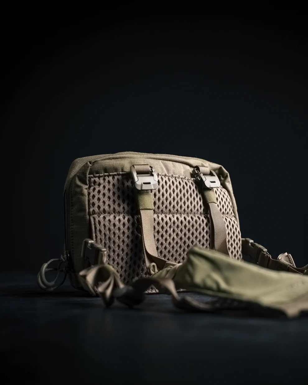Das EBERLESTOCK Force Chest Pack, eine braune, MOLLE-kompatible taktische Tasche, verfügt über eine Netzrückwand, verstellbare Gurte und Metallschnallen. Auf einer dunklen Oberfläche unterstreicht die gut beleuchtete Textur die robuste Handwerkskunst.