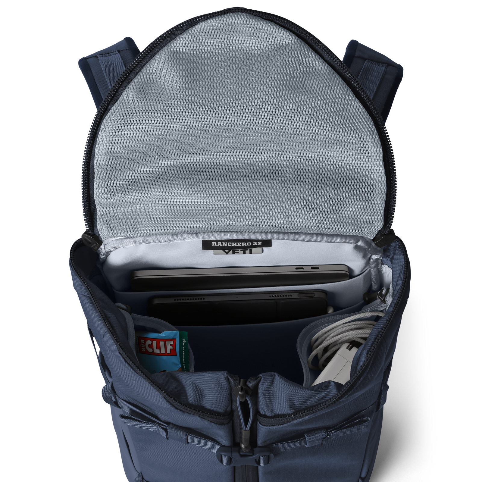 Der YETI® Rucksack Ranchero™ 22L in Classic Navy ist wasserfest und lässt sich öffnen, um Laptop, Tablet, CLIF Bar, Ladekabel, Mesh-Innentasche und YETI-Branding zu enthüllen. Er verfügt über ein spezielles Laptop-Fach für die sichere Aufbewahrung von Geräten.