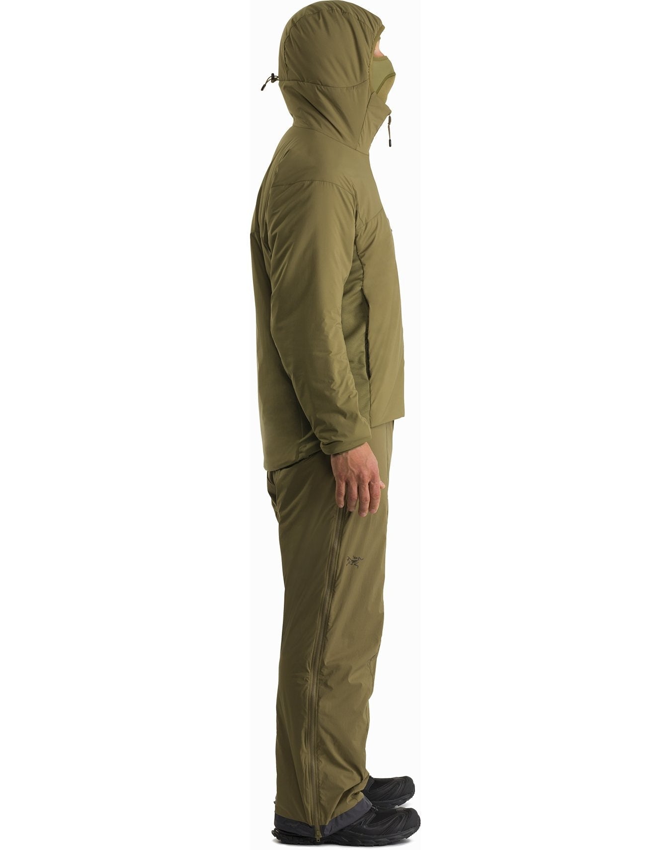 Eine Person steht im Profil, nach links blickend, vor einem weißen Hintergrund und trägt den ARC'TERYX LEAF Arc'teryx Atom Hoody LT Gen2.1 in Schwarz mit passender Hose und schwarzen Schuhen.