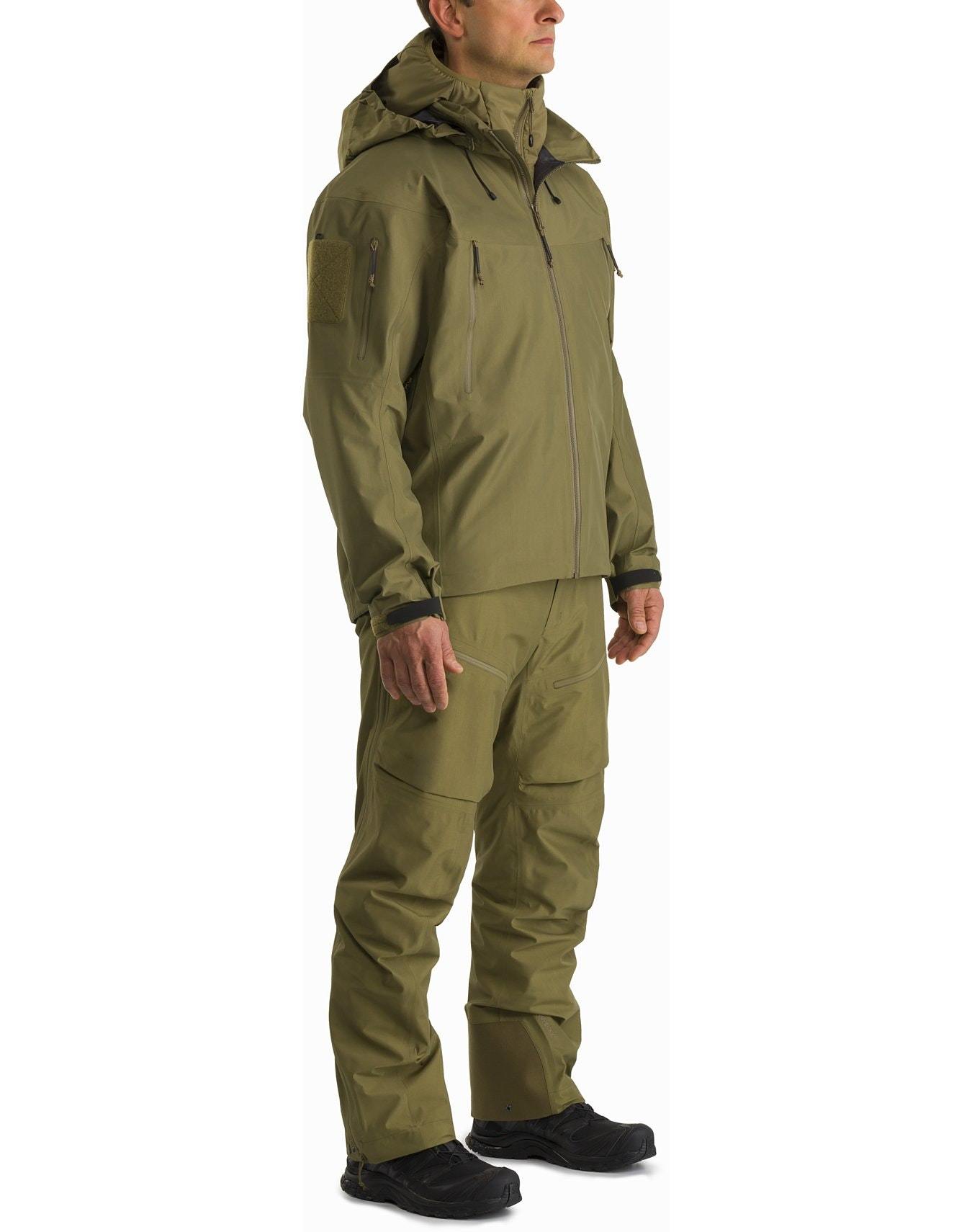 Eine Person trägt einen ARC'TERYX LEAF Arc'teryx Atom Hoody LT Gen2.1 in Crocodile, gepaart mit einer passenden Multi-Pocket-Hose und schwarzen Schuhen, die einen Outdoor- oder taktischen Look kreieren.