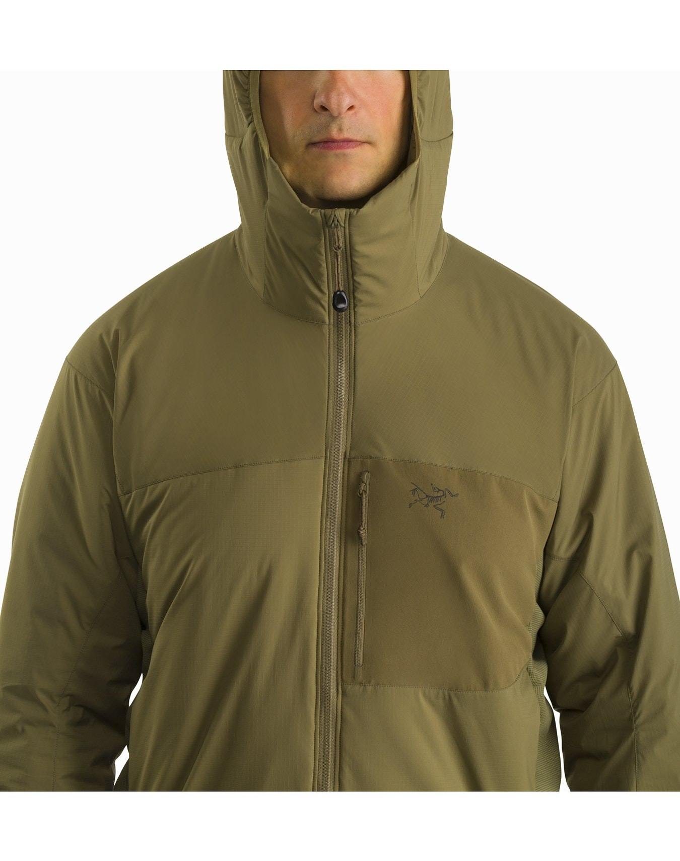 Eine Person trägt die ARC'TERYX LEAF Arc'teryx Atom Hoody LT Gen2.1 in Ranger Green, eine leichte, isolierte Herrenjacke mit einem Frontreißverschluss und einer Brusttasche. Die Kapuze ist hochgezogen und verdeckt teilweise das Gesicht.