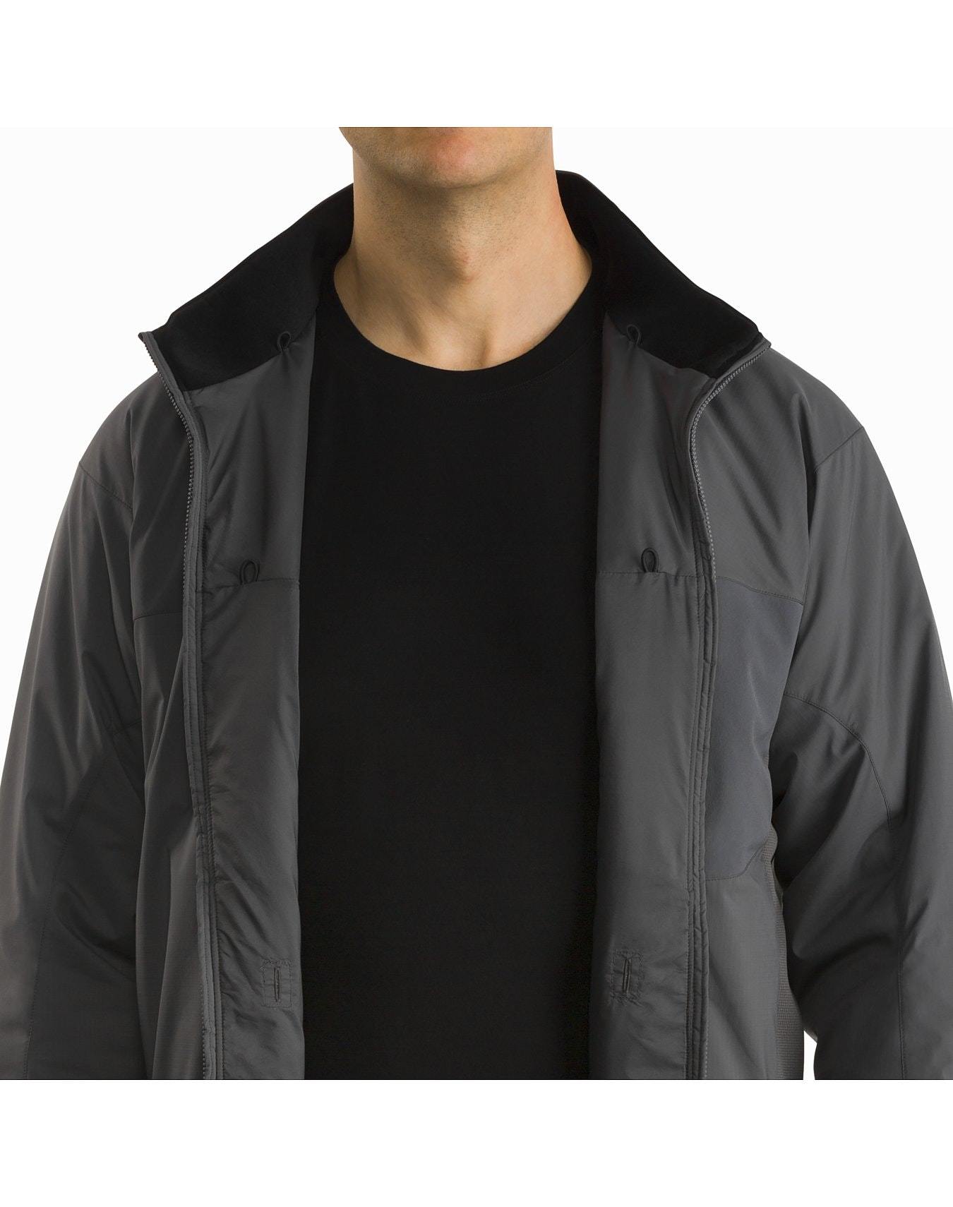 Eine Person trägt eine ARC'TERYX LEAF Arc'teryx Atom Jacket LT Gen2.1 in Ranger Green ohne Reißverschluss über einem schwarzen Hemd, das POLARTEC Power Stretch-Gewebe offenbart, vor einem einfarbig weißen Hintergrund; dargestellt von den Schultern zum Mund.