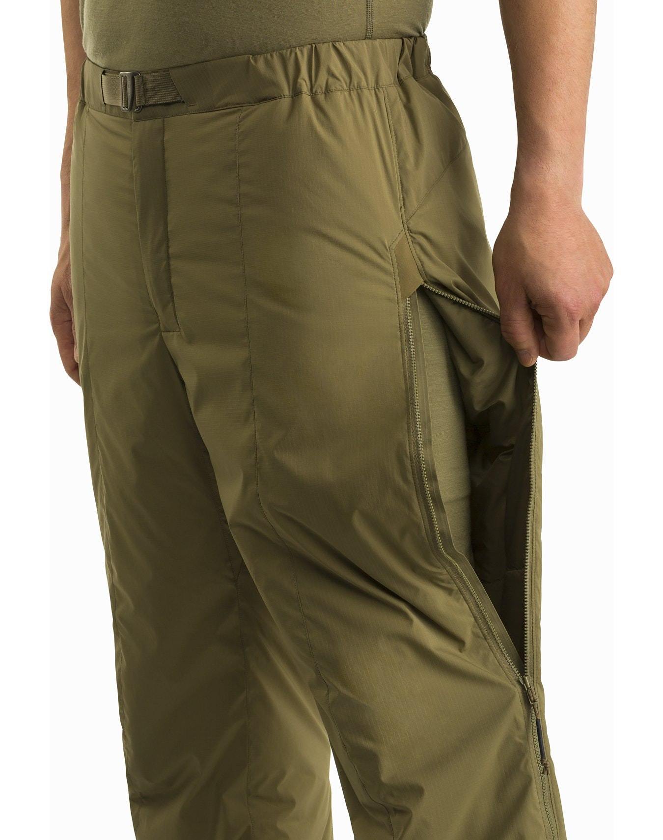 Eine Person, die die schwarze Arc'teryx Atom Pant LT Gen2 von ARC'TERYX LEAF trägt, hält mit einer Hand den großen Seitenreißverschluss offen, so dass das Innenfutter zum Vorschein kommt und die Belüftungsfunktion der Hose durch den Reißverschluss sichtbar wird.