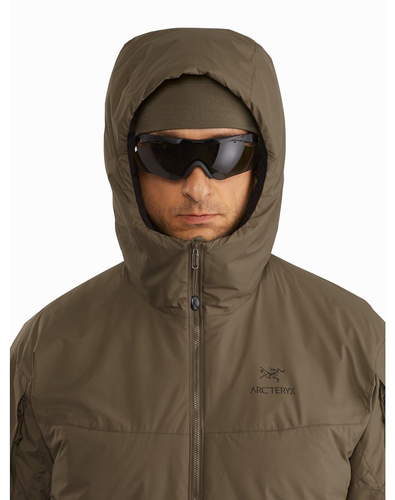 Eine Person trägt ein schwarzes Arc'teryx Cold WX Hoody LT Gen2.1 by ARC'TERYX LEAF, eine dunkle Sonnenbrille und ein passendes Stirnband und schaut nach vorne. Der Kapuzenpulli zeigt das Arc'teryx-Logo auf der Brust vor einem weißen Hintergrund.