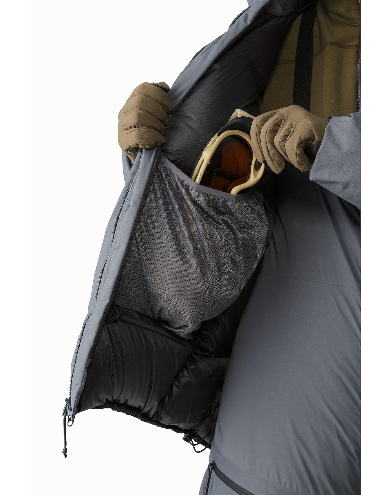 Nahaufnahme der grauen, isolierten Innenseite des ARC'TERYX LEAF Arc'teryx Cold WX Parka SVX - Wolf. Sie zeigt eine große Netztasche für Skibrillen, die mit Handschuhen geöffnet werden kann und Wärme und sichere Aufbewahrung auf der Piste bietet.