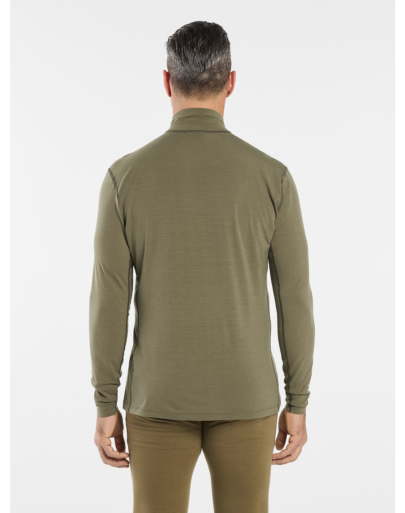 Ein Mann mit kurzen dunklen Haaren ist von hinten zu sehen. Er trägt ein ARC'TERYX LEAF Arc'teryx Cold WX Zip Neck AR - Crocodile Oberteil und eine passende Hose, einfach gestylt vor einem schlichten weißen Hintergrund.