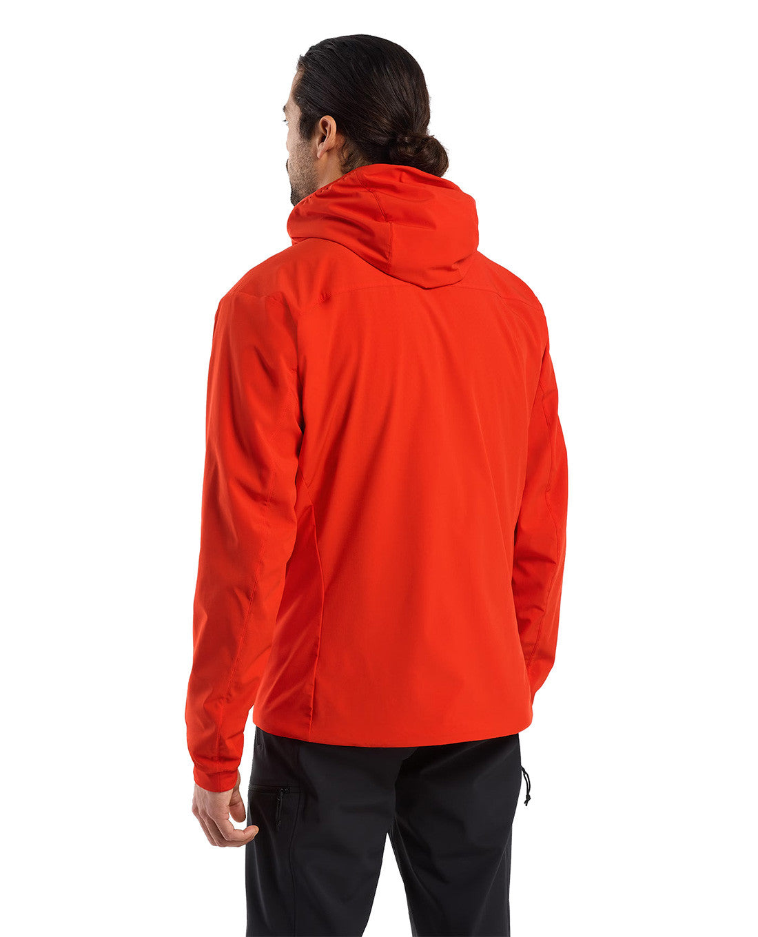 Eine Person mit langen, nach hinten gebundenen dunklen Haaren, bekleidet mit einem leuchtend roten ARC'TERYX PRO Arc'teryx Practitioner AR Hoody Men's - Dynasty und einer schwarzen Hose, steht von der Kamera abgewandt vor einem weißen Hintergrund.