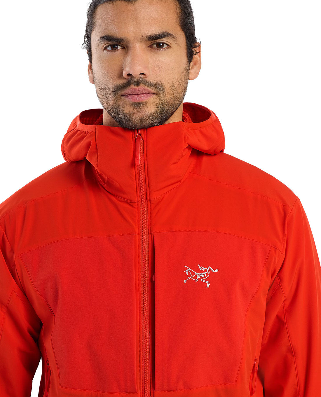 Ein Mann blickt vor einem weißen Hintergrund nach vorne. Er trägt den leuchtend roten ARC'TERYX PRO Arc'teryx Practitioner AR Hoody Men's - Dynasty mit Brustlogo, Frontreißverschluss und atmungsaktiver Synthetikisolierung.