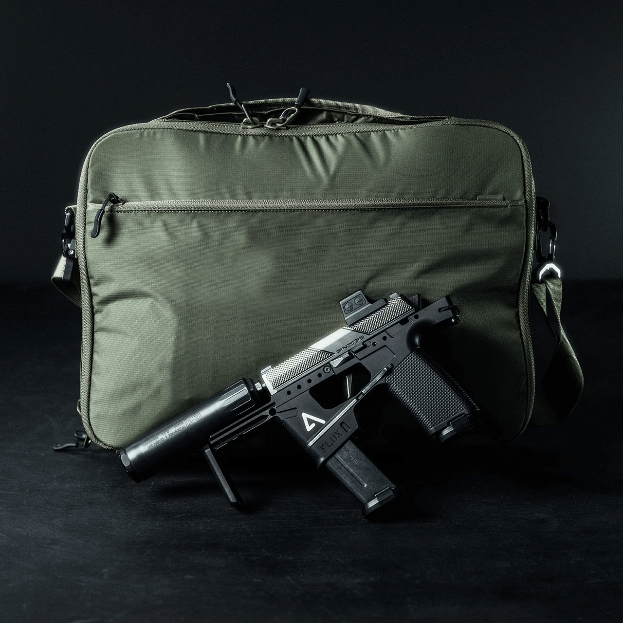 Eine kompakte schwarz-silberne Schusswaffe mit Schalldämpfer ruht vor einem EBERLESTOCK Fade Brief aus der Eberlestock Fade Brief Kollektion vor einem dunklen Hintergrund.