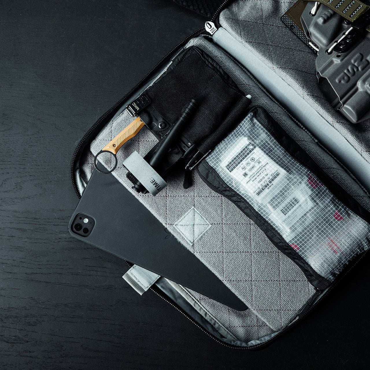 Öffnen Sie die EBERLESTOCK Fade Brief mit organisierten Fächern für ein schwarzes Smartphone, Werkzeug, einen Stift, einen Aufnäher mit Text, ein Lineal und andere Utensilien - perfekt für Arbeit und Alltag.