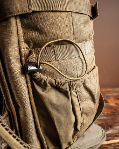 Nahaufnahme des EBERLESTOCK Eberlestock Gunrunner Pack - Mountain, mit einer braunen Seitentasche mit elastischem Kordelzug und Kunststoffschnurverschluss, die das strapazierfähige Material und die detaillierten Nähte zeigt.