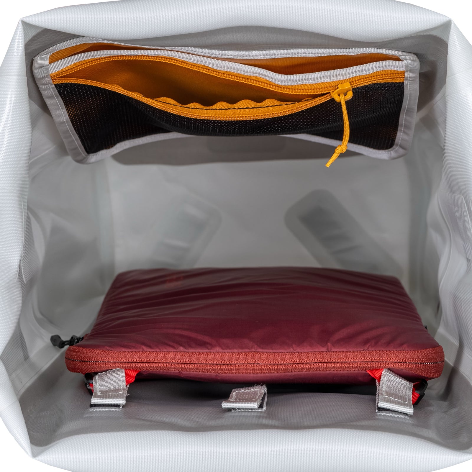 Der EXPED Rucksack Torrent 45 verfügt über einen geräumigen Innenraum mit einer orangefarbenen Netztasche mit Reißverschluss an der Oberseite und einer kastanienbraunen gepolsterten Tasche mit zwei grauen Trägern an der Unterseite - ideal für organisierte Trekkingabenteuer.
