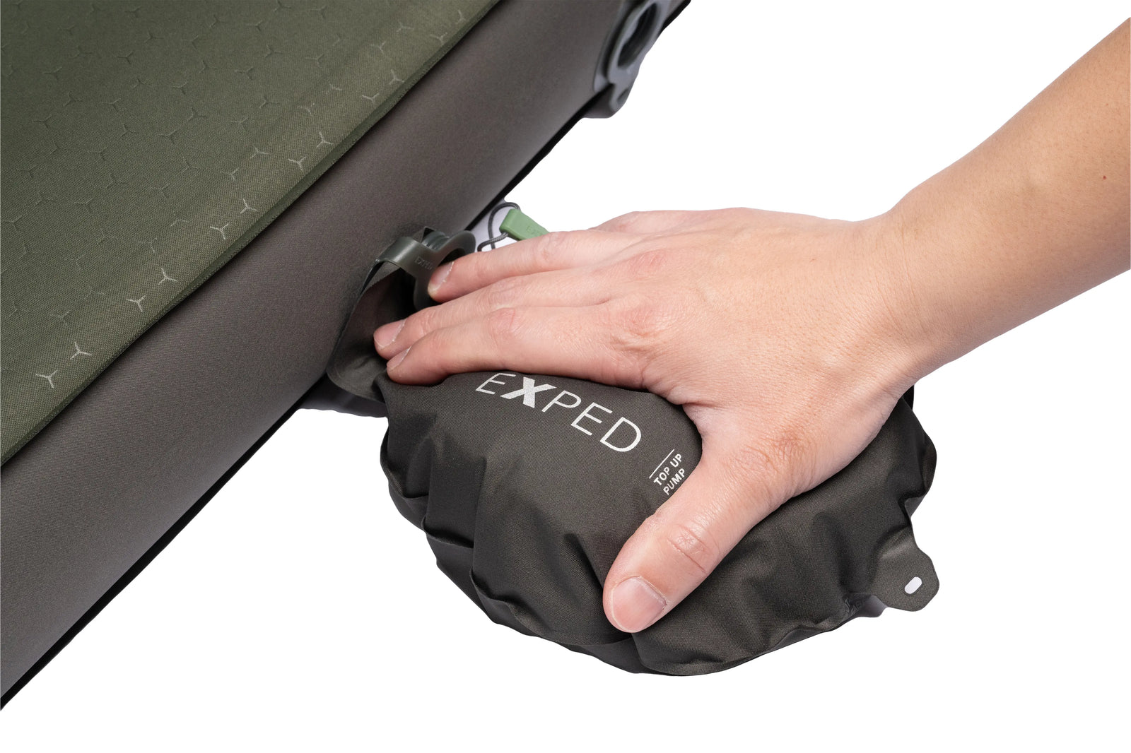 Eine Hand drückt auf einen schwarzen EXPED-Pumpsack, der an einer olivgrünen Exped Schlafmatte MegaMat Auto von EXPED befestigt ist, und bläst so die selbstaufblasende Schlafmatte mit ihrem sechseckigen Muster auf.
