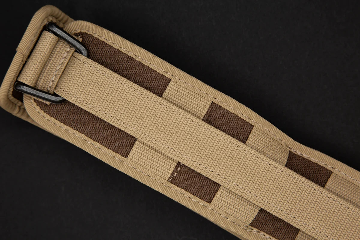 Eine Nahaufnahme der Extrema Ratio Messer COL Moschin Desert Warfare von EXTREMA RATIO zeigt ihr hellbraunes Stoffband mit braunen rechteckigen Akzenten und einer Metallschließe auf schwarzem Hintergrund.