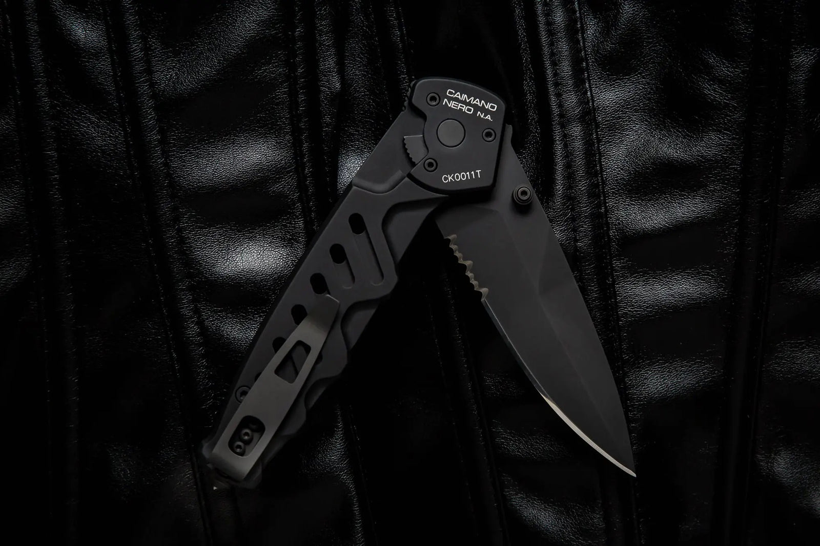 Das Extrema Ratio Messer Caimano Nero N.A. Klappmesser von EXTREMA RATIO mit teilweise gezahnter Klinge und kantigem Griff liegt auf einer glänzenden schwarzen Lederoberfläche.