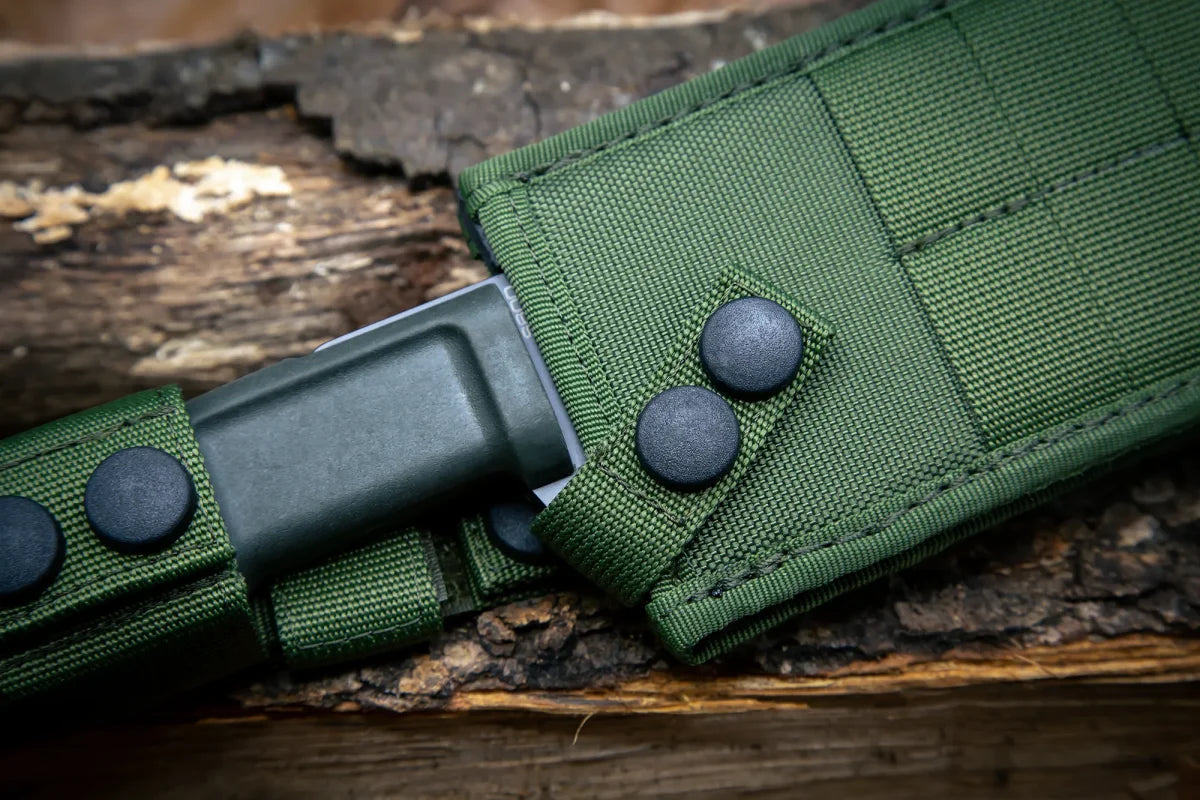 Nahaufnahme des EXTREMA RATIO Ontos II S600 Black Griffs, teilweise ummantelt von einem grünen Stoffetui mit schwarzen Druckknöpfen und auf rauem Holz ruhend - ein Outdoormesser erster Wahl.
