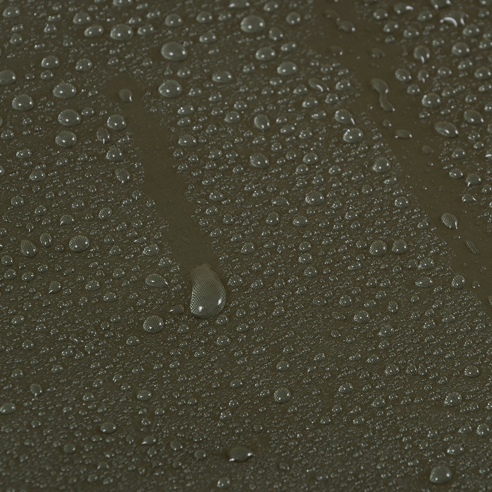 Nahaufnahme von Wassertropfen, die auf der dunklen, strukturierten Oberfläche der Highlander Hängematte Hängematte Crusader Waterproof von HIGHLANDER FORCES abperlen und die Wasserbeständigkeit der Hängematte unterstreichen, während sich die Tropfen in verschiedenen Größen über das Material verteilen.