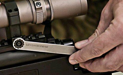 Eine Hand benutzt das LEATHERMAN Leatherman MUT® BLACK Multitool, um die Zielfernrohrhalterung eines Gewehrs einzustellen, wobei der Schwerpunkt auf dem Werkzeug und dem verwendeten Zielfernrohr liegt.