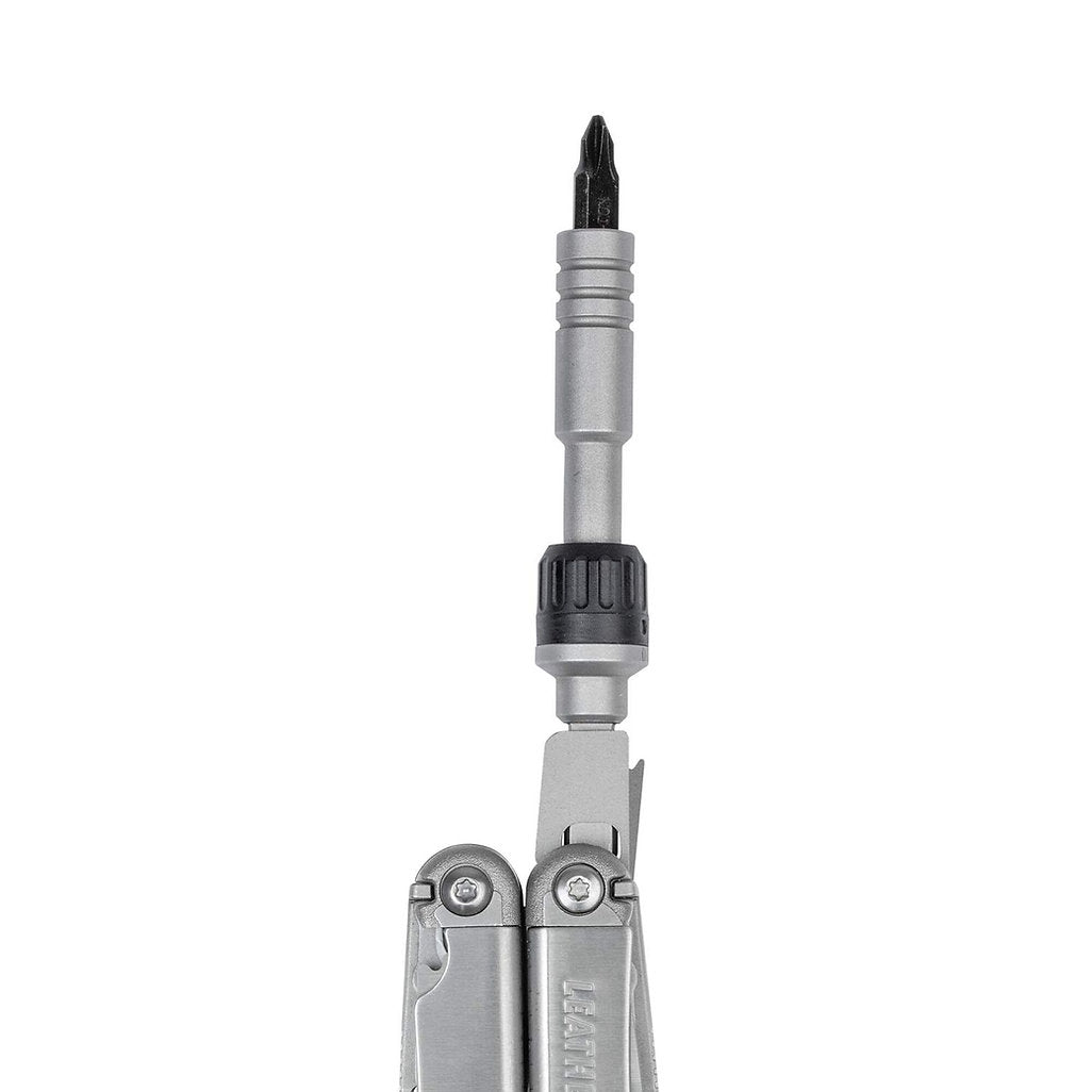 Eine Nahaufnahme zeigt das Multitool LEATHERMAN RATCHET DRIVER mit verlängertem Schraubendrehereinsatz und schwarzem Griff, während der metallene LEATHERMAN RATCHET DRIVER mit magnetischem Bithalter teilweise am unteren Bildrand erscheint.