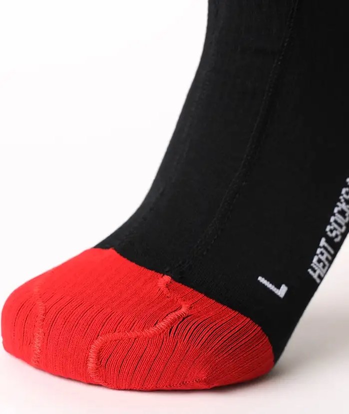 Die Nahaufnahme zeigt einen Fuß, der die LENZ Lenz Heizsocken 6.1 Toe Cap Merino Compression Socke in schwarz mit roter Spitze trägt, mit der Aufschrift "L" und "LEFT SOCK" für den linken Fuß, vor einem schlichten weißen Hintergrund.