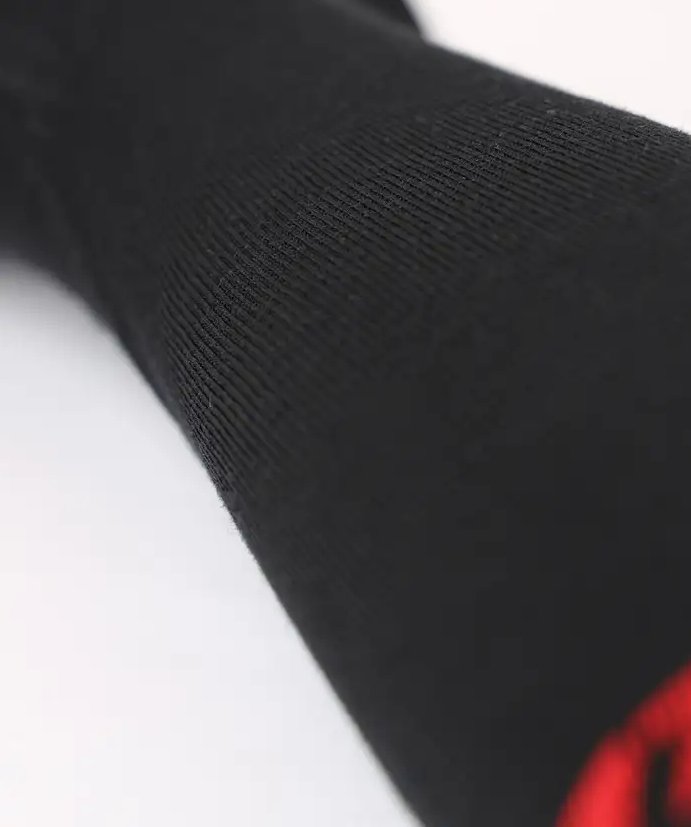 Nahaufnahme der LENZ Lenz Heizsocken 6.1 Toe Cap Merino Compression Socke in Schwarz mit gerippter Textur und einem Hauch von Rot an der Spitze, vor einem schlichten weißen Hintergrund.