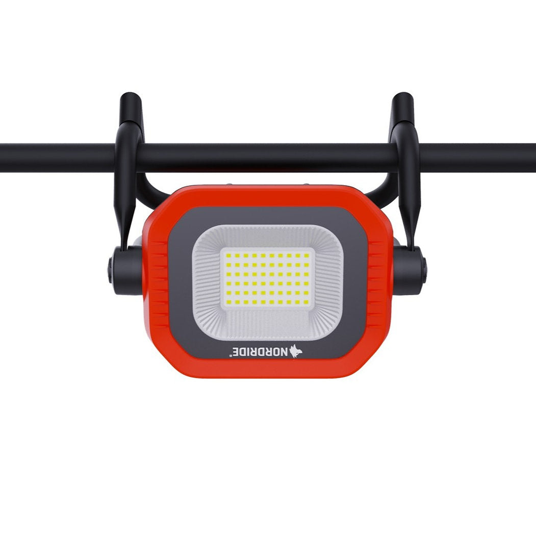 Ein rot-schwarzer NORDRIDE Arbeitsstrahler Sector 50W R, montiert auf einer horizontalen schwarzen Stange und von vorne gesehen vor einem weißen Hintergrund - ideal für Baustellen.