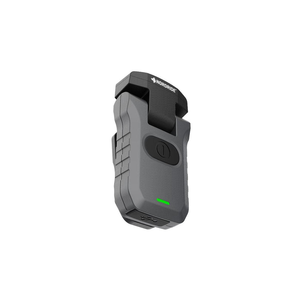 Eine kompakte graue NORDRIDE Clipleuchte Patrol UV-Lampe mit einem schwarzen Clip, einem großen zentralen Knopf, einer grünen Kontrollleuchte und dem NORDRIDE-Logo auf der Oberseite.