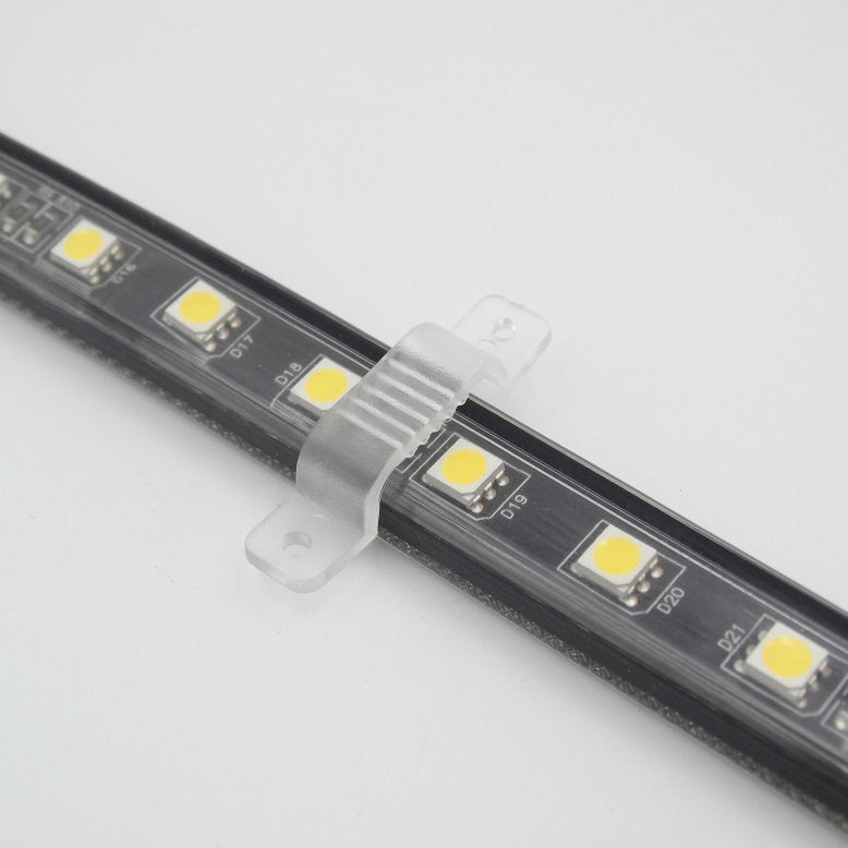Eine Nahaufnahme des NORDRIDE Lichtbandes Viper LED 25m in schwarz, befestigt mit einem transparenten Montageclip auf einer weißen Fläche - ideal für die Baustellenbeleuchtung und vielseitig einsetzbar als Arbeitslichtschlauch.