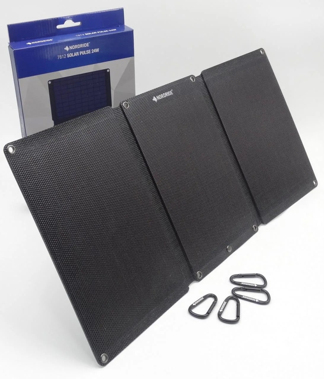 Die NORDRIDE SOLAR PULSE 24W ist aufgeklappt dargestellt und zeigt ihr faltbares Solarpanel mit Karabinern und der im Hintergrund sichtbaren Verkaufsverpackung.