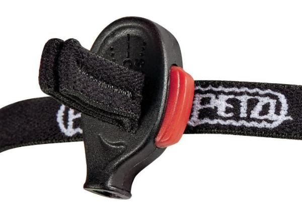 Nahaufnahme eines schwarzen Kunststoffknebels mit rotem Akzent auf einem schwarz-weißen Band, Teil der ultrakompakten PETZL e+LITE®-Stirnlampe (50 Lumen), ideal für Notfälle oder die Verwendung mit Sicherheits- und Sporthelmen.