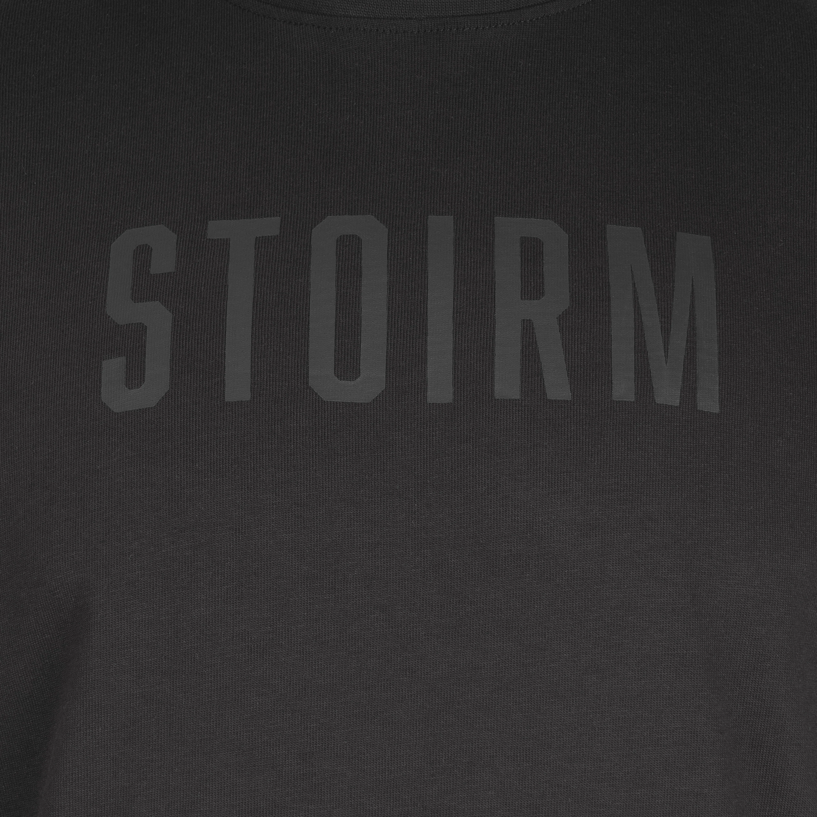 Nahaufnahme des STOIRM Cotton T-Shirt - Black von STOIRM, mit auffälligem, tonalem Branding auf der Brust. Dieses schwere Baumwoll-T-Shirt bietet eine Mischung aus Stil und Strapazierfähigkeit für den täglichen Gebrauch.