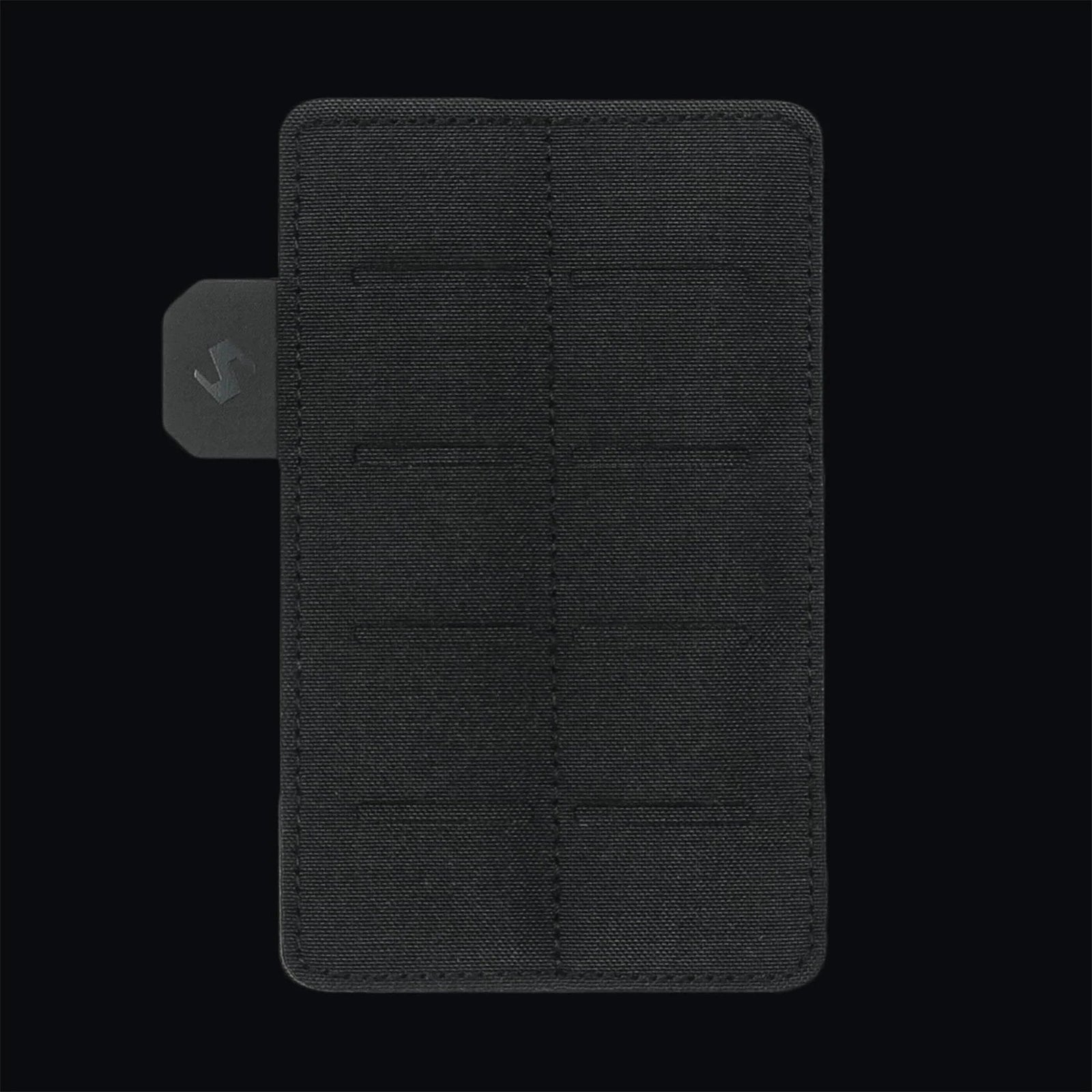 Das STOIRM Small Molle Panel Portemonnaie zeichnet sich durch ein schwarzes, minimalistisches Stoffdesign mit Gitternähten und einer kleinen grauen Metall-Logo-Lasche auf der linken Seite aus, inspiriert vom Molle Panel Black, das vor einem schwarzen Hintergrund abgebildet ist.