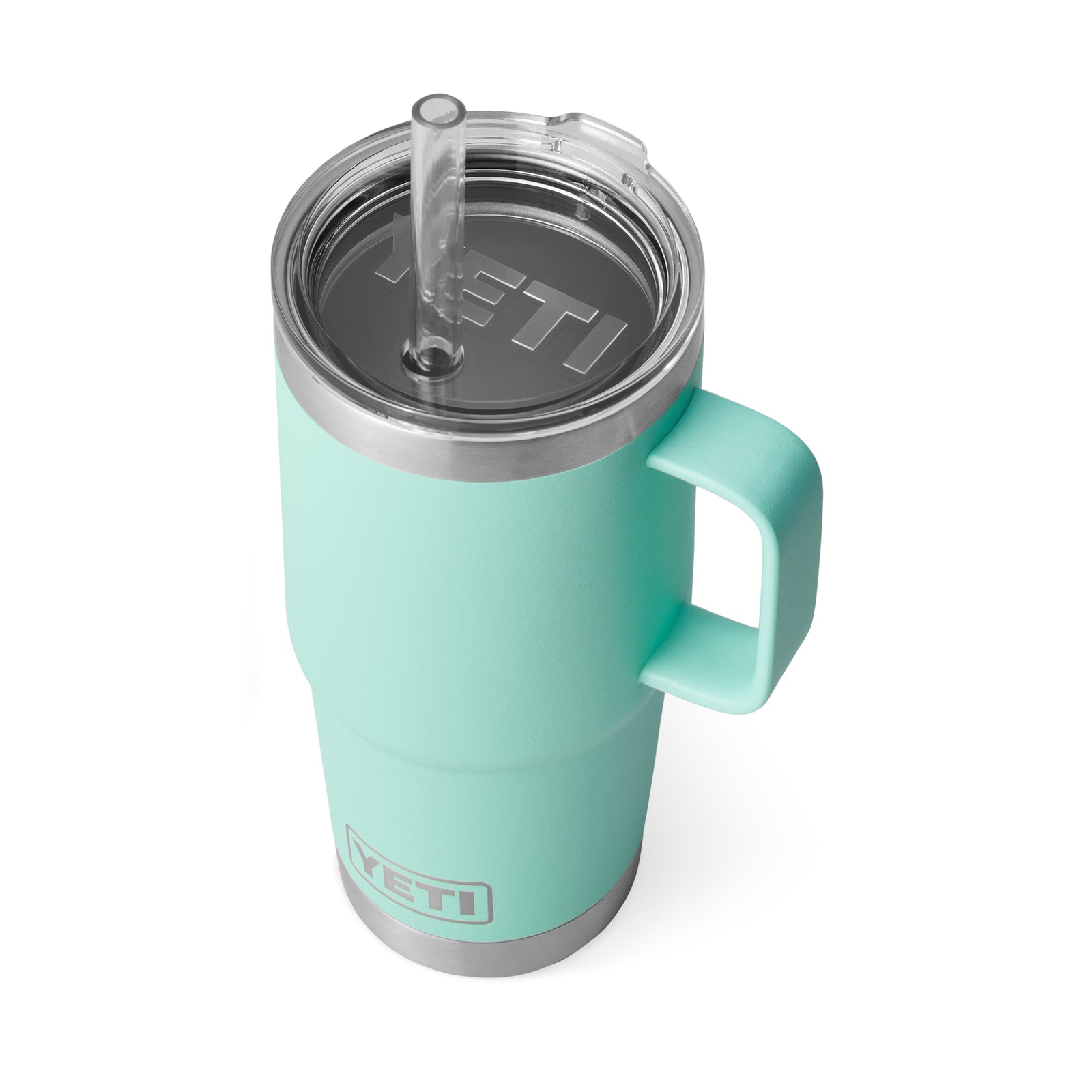 Ein YETI® Becher Rambler 25 Oz Straw Mug in Seafoam, mit Henkel, durchsichtigem Deckel mit Strohhalm und YETI-Logo auf Becher und Deckel, dargestellt aus einem erhöhten Winkel auf weißem Hintergrund.