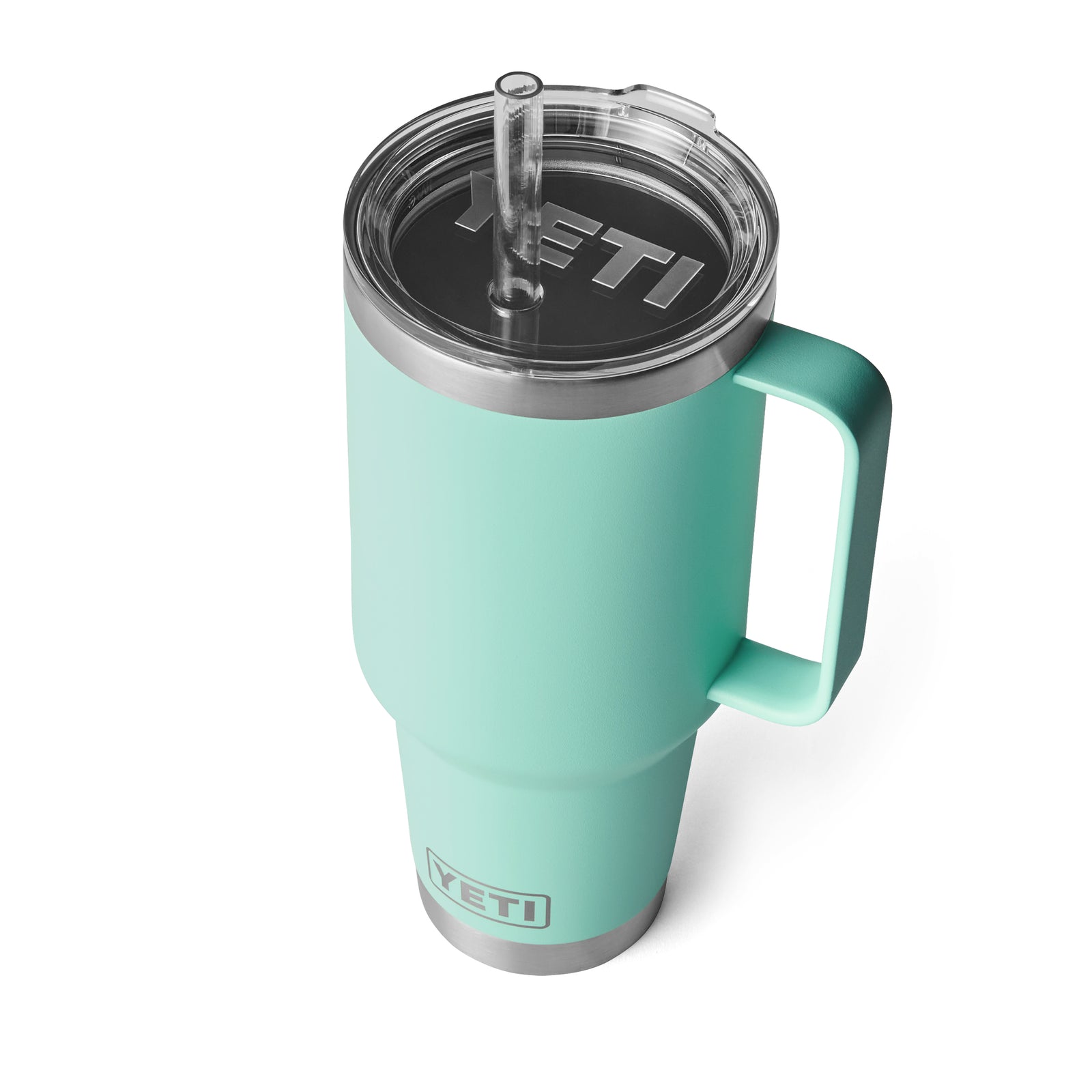 Der YETI® Becher Rambler 42 Oz Straw Mug - Seafoam ist auf weißem Hintergrund abgebildet und hat einen Henkel, einen durchsichtigen Kunststoffdeckel, einen Strohhalm und eine doppelwandige Vakuumisolierung. Das YETI-Logo erscheint sowohl auf dem Deckel als auch auf dem Becher.