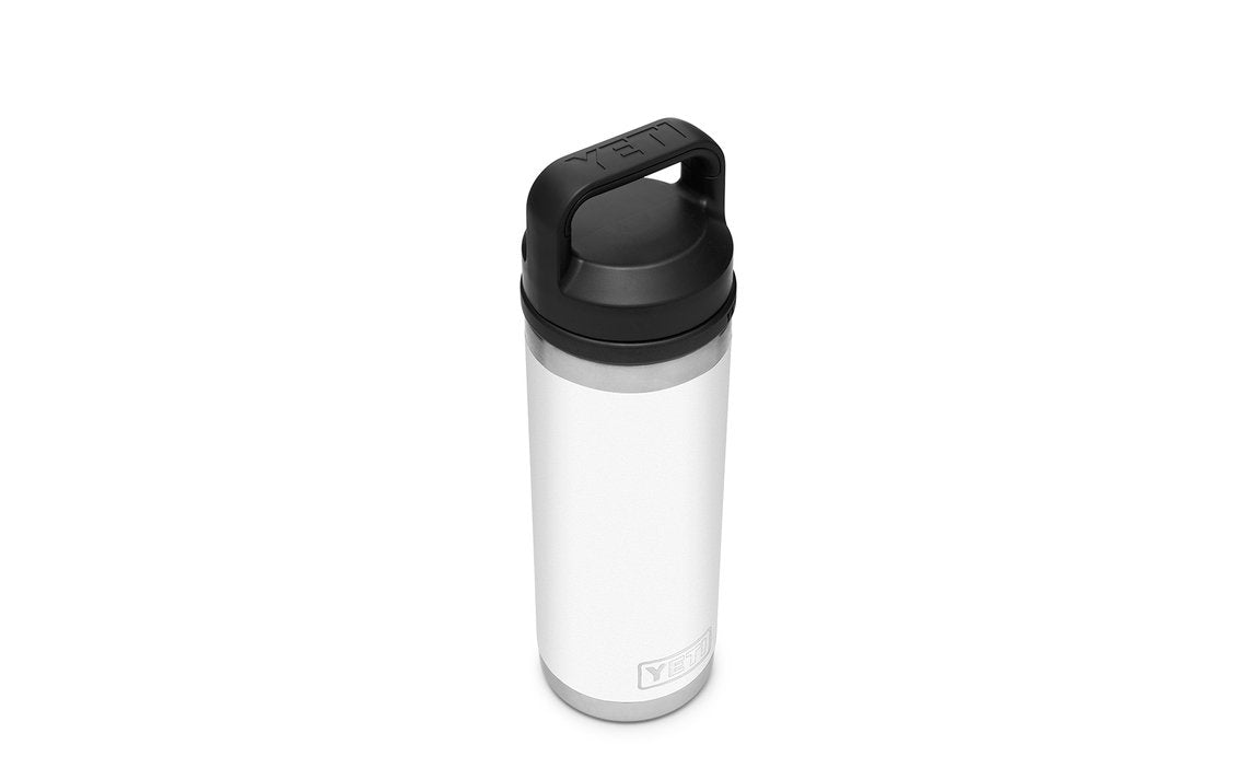 Die YETI® Flasche Rambler 18 Oz in Weiß steht aufrecht vor einem schlichten weißen Hintergrund, verfügt über einen schwarzen Schraubdeckel und Griff, mit dem YETI-Logo in der Nähe des Bodens und doppelwandige Vakuumisolierung für optimale Temperaturerhaltung.