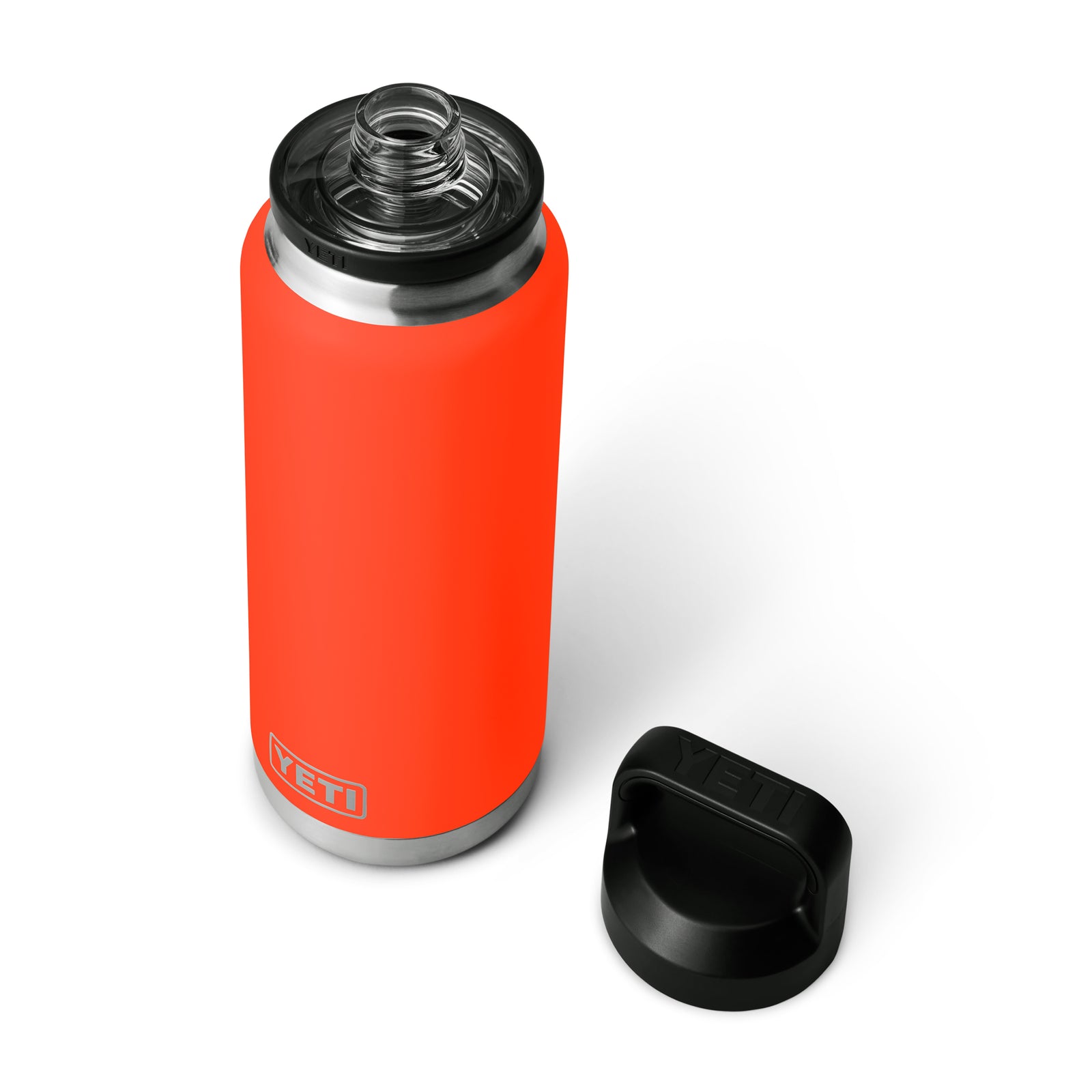 Die YETI® Flasche Rambler 36 Oz - Solare Flare, eine leuchtend orange vakuumisolierte Flasche von YETI mit Edelstahlrand, ist ohne schwarzen Schraubdeckel dargestellt. Der Deckel liegt rechts daneben auf weißem Hintergrund.