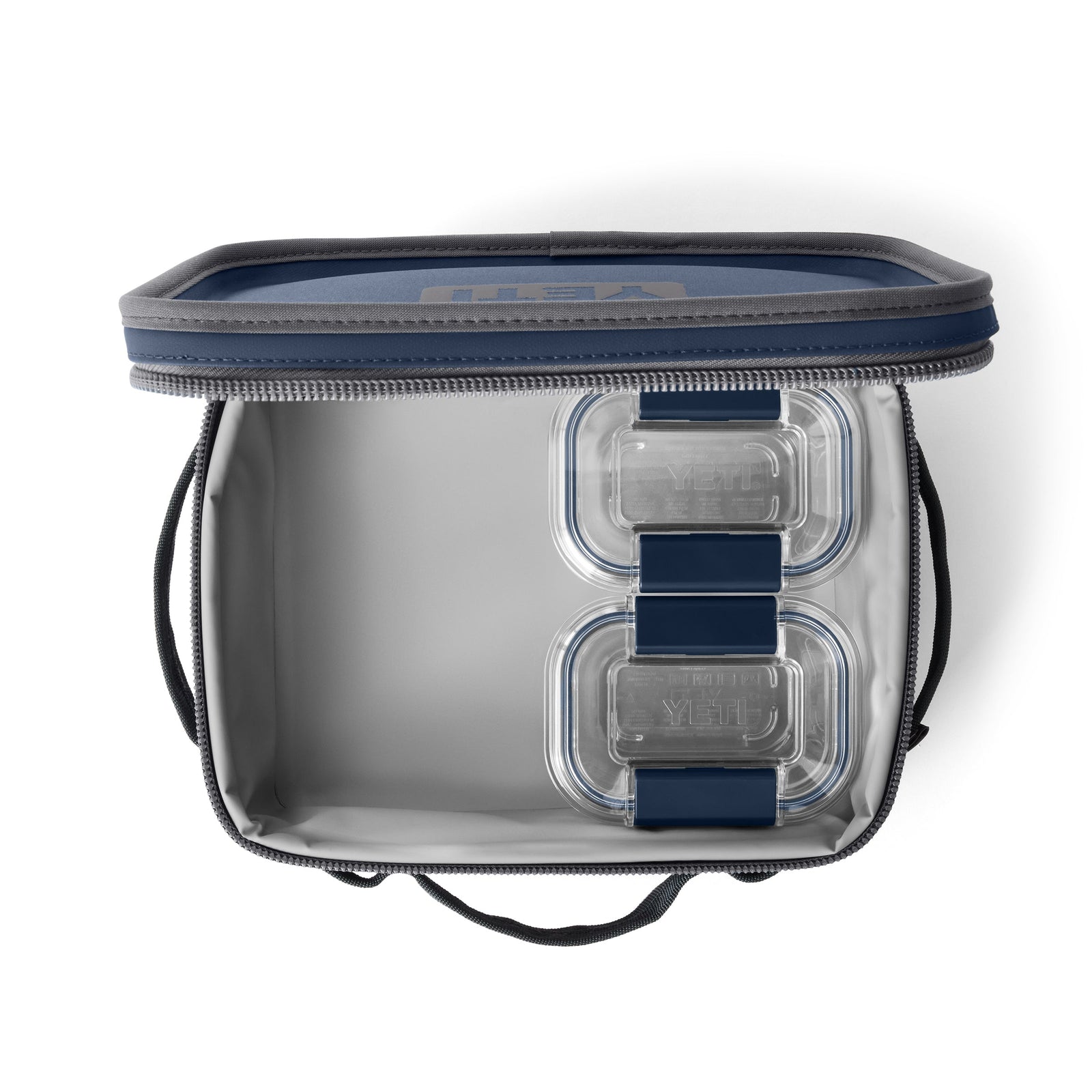 Eine offene, leere isolierte Lunch-Tasche mit grauem Innenraum, marineblauem Rand und zwei YETI® Food Storage Small-Behältern, die auf der rechten Seite gestapelt sind.