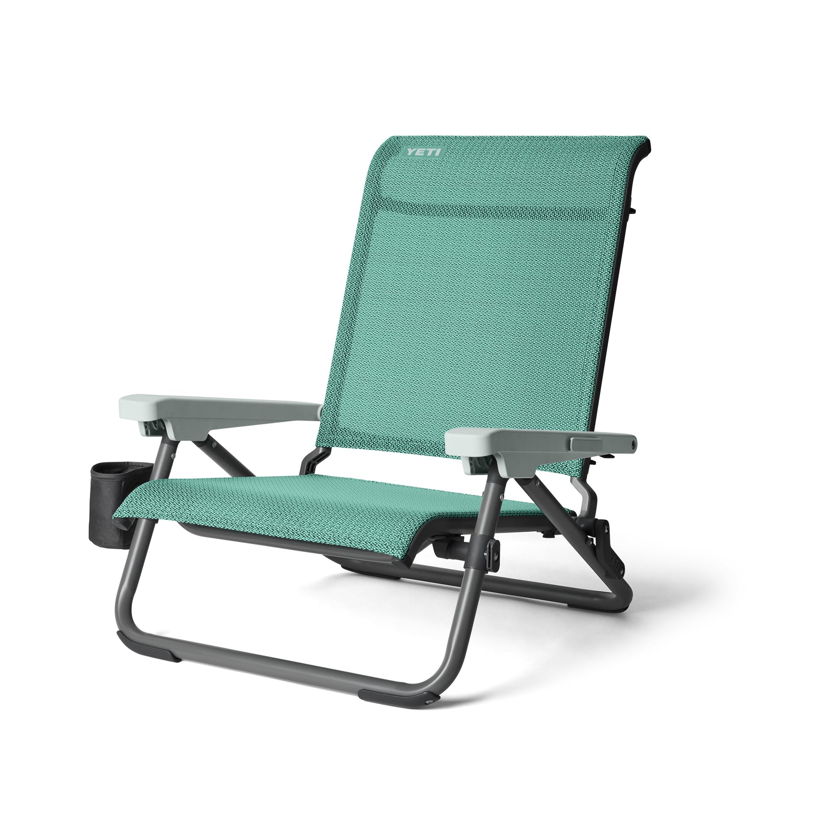 Der YETI® Hondo Beach Chair - Seafoam ist ein faltbarer Outdoor-Stuhl mit grauen Armlehnen, einem schwarzen Rahmen und einem eingebauten Becherhalter auf der linken Seite. Das YETI-Logo befindet sich oben an der Rückenlehne.